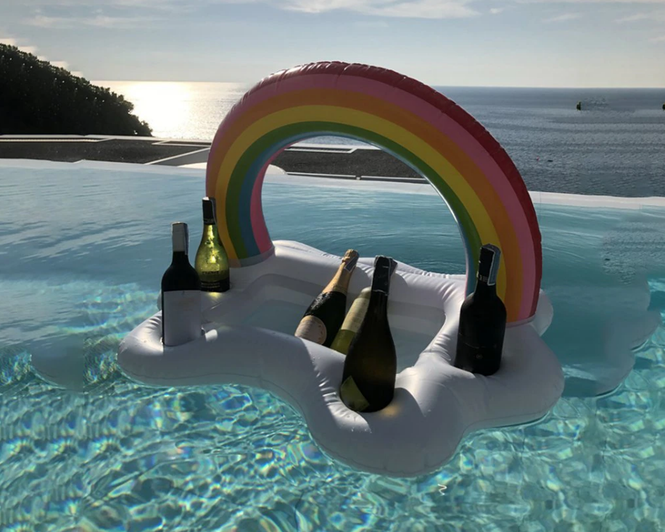 Inflatable rainbow-shaped float with champagne bottles in a pool